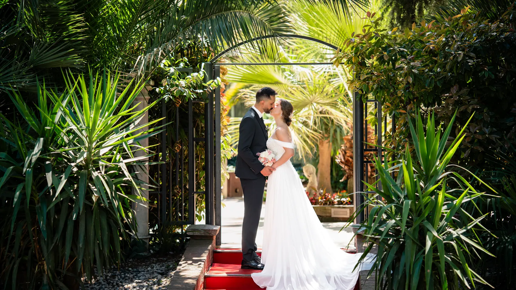 Andrei e Irene se besan bajo el arco del jard&iacute;n el d&iacute;a de su boda